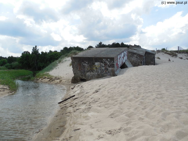 Rzeka na plaży, obok niej betonowe, kwadratowe elementy