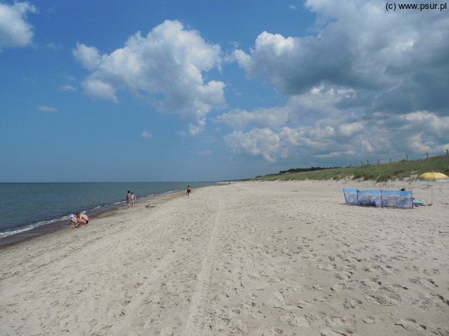 Szeroka i niemal pusta plaża w słoneczny dzień