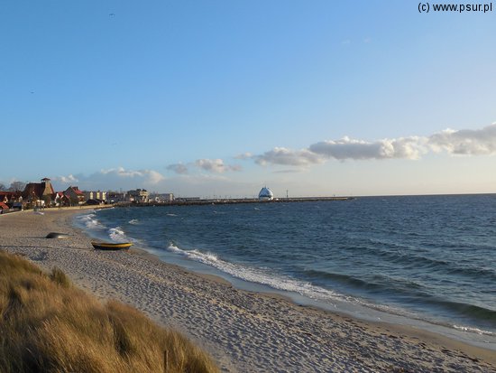 Plaża z kutrem i port na drugim planie