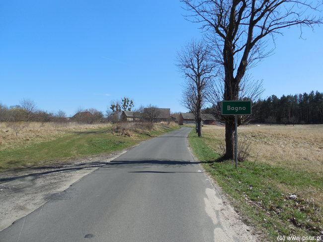 Szosa z tabliczką oznaczającą początek wsi Bagno