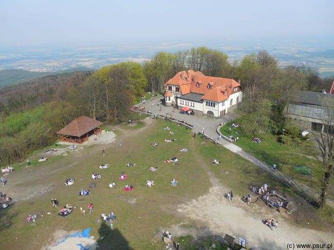 Widok na polanę na szczycie z góry: odpoczywający ludzie, schronisko