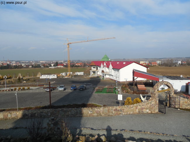 Duży cień figury padający na nowy budynek Domu Pielgrzyma